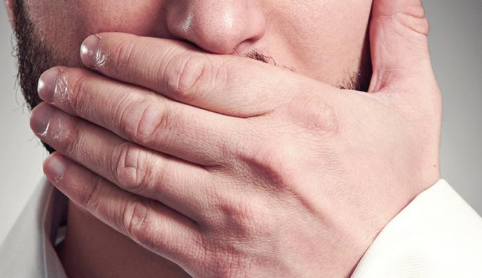 Young Adult Man Holding Hand Over His Mouth Over Grey Background