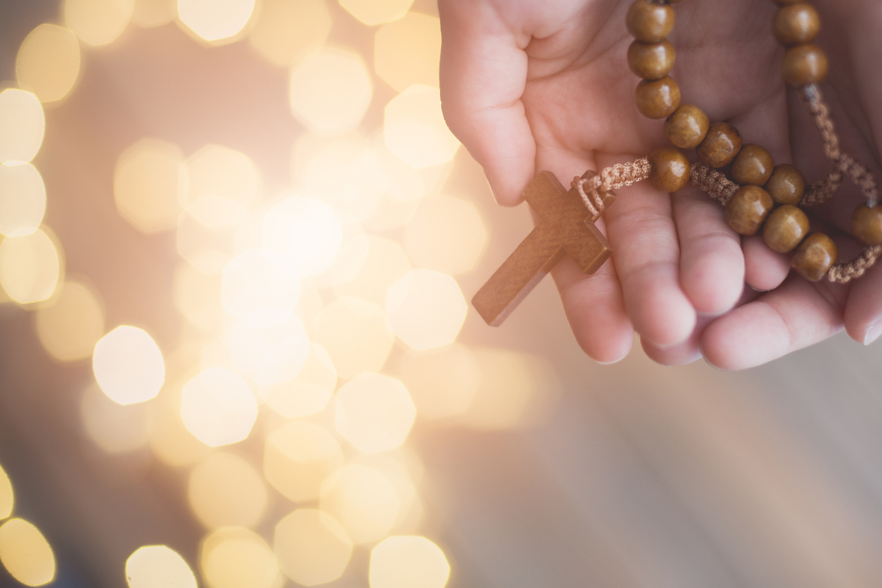 Little Boy Child Praying And Holding Wooden Rosary.